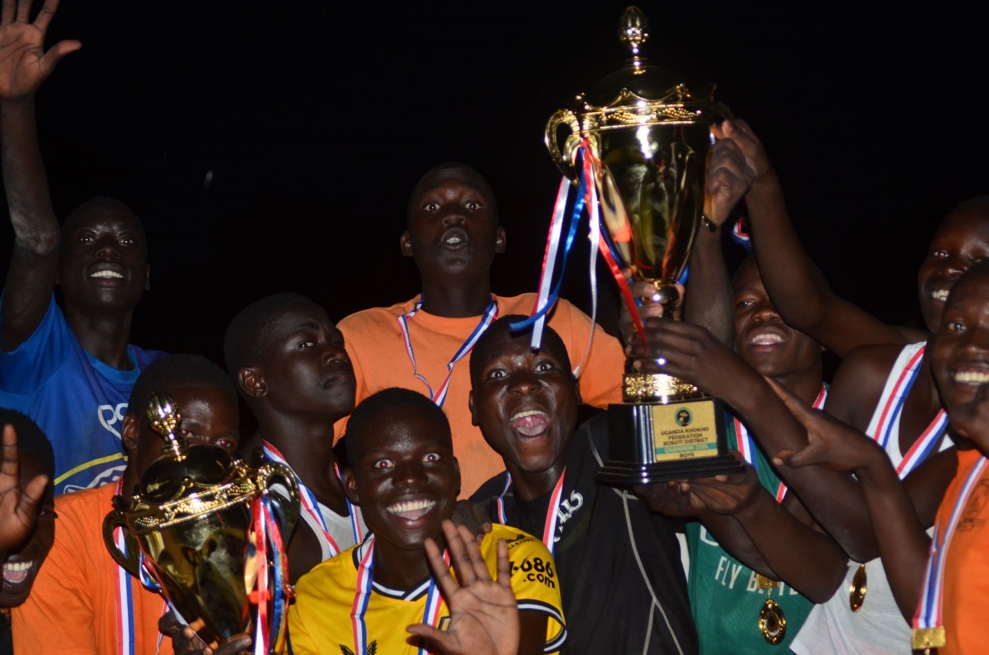 Cornerstone SS players hold up the trophy and medals at night to celebrate