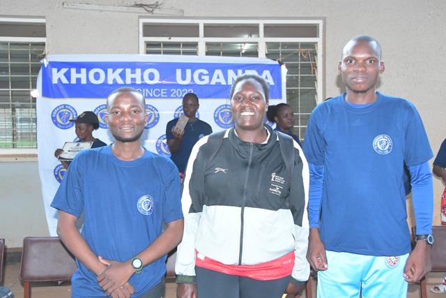 Three members of the course team in front of the banner