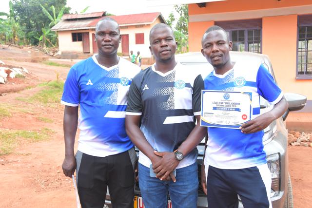 Three participants with a certificate beside a car