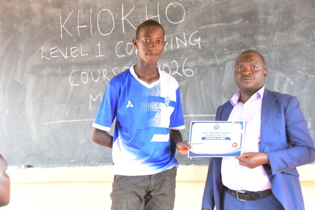 A participant receives her certificate from the trainer at the blackboard