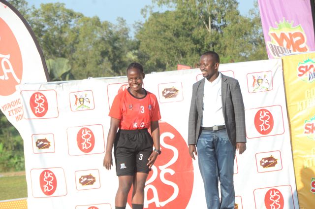 A player in red kit poses with an official at the Ball Games II backdrop